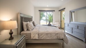 Une chambre à coucher comprenant un lit, une table de chevet, une commode et un grand miroir.