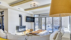 A modern living room with a fireplace, sofa, and a TV mounted on the wall. - 105 Verbier Building 12 (Mont-Tremblant)
