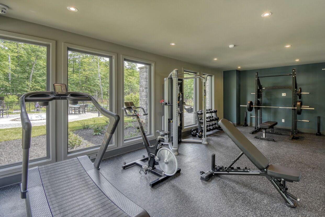 Ein Fitnessstudio mit Cardiogeräten, Gewichten und Bänken.