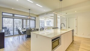 A modern kitchen with a large island, built-in oven, and ample natural light from large windows. - 105 Verbier Building 12 (Mont-Tremblant)