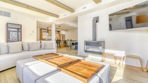 A modern living room with a sofa, ottomans, a fireplace, and a dining area in the background. - 105 Verbier Building 12 (Mont-Tremblant)