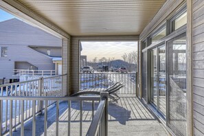 A covered outdoor area with a metal railing, a view of a parking lot, and a building in the background. - 105 Verbier Building 12 (Mont-Tremblant)