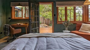Une chambre à coucher comprenant un lit, un bureau, une chaise, un canapé et donnant sur l’extérieur.