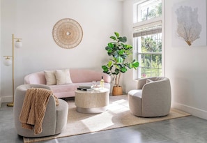 A modern living room with a pink sofa, round coffee table, and a grey armchair. - 2 Villas, Pickleball,Heated pool, Naples escape. (Naples)