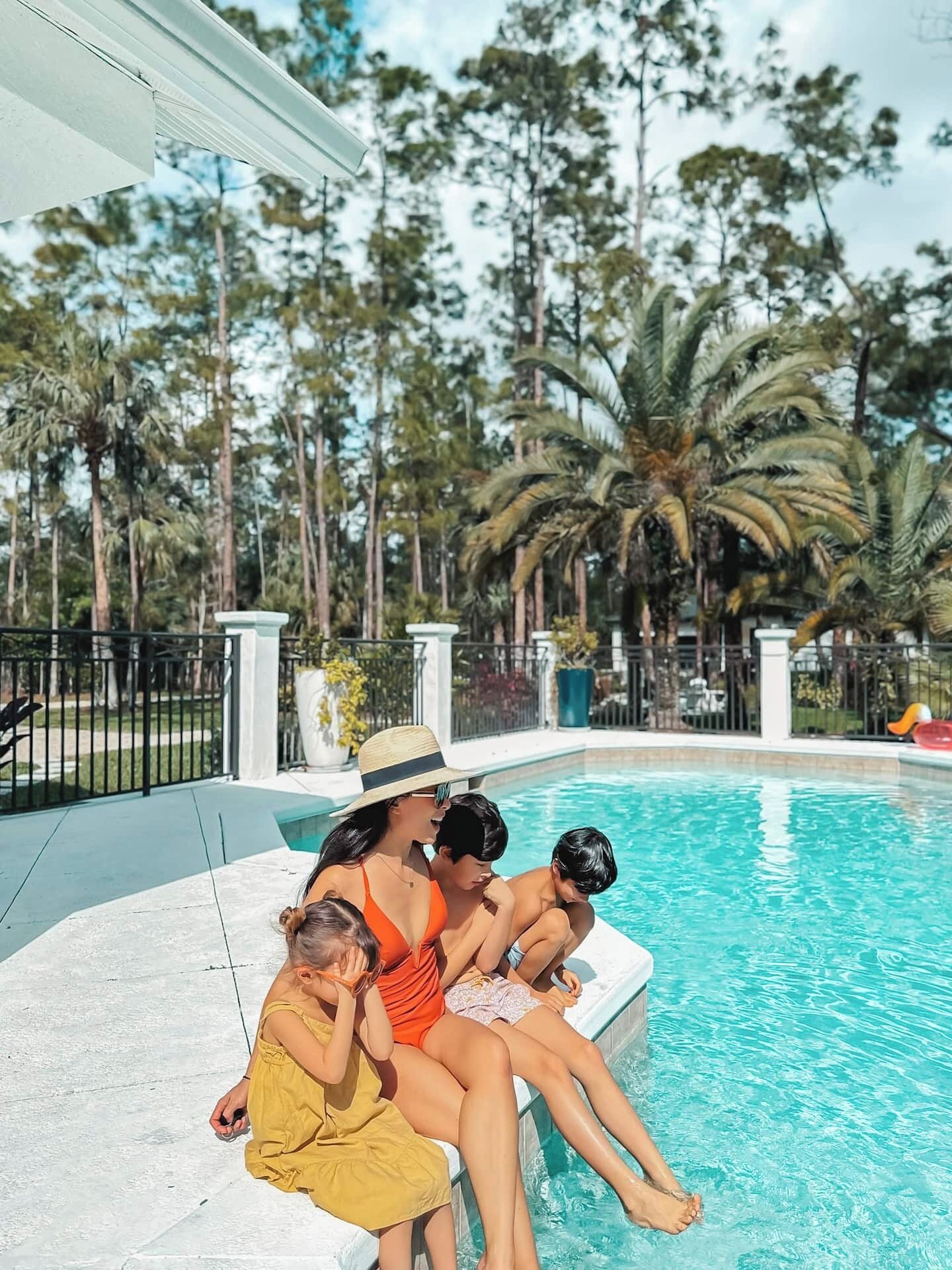A pool area with a family sitting by the edge.