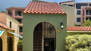 Een gebouw met een pannendak, een groene entree en een metalen poort.