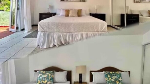 Quarto de hotel com uma cama grande, duas camas menores, uma mesa de cabeceira com abajur e uma porta de vidro que se abre para uma varanda.