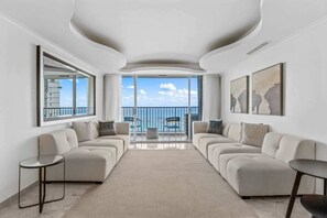 A modern living room with a sofa set, a coffee table, and a view of the balcony. - Modern Ocean Front Apt @ESJ (Carolina)