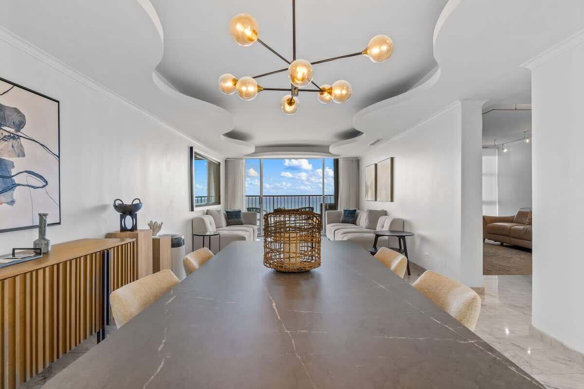 Une salle de conférence spacieuse, dotée d’une grande table, d’un lustre moderne et de sièges confortables.