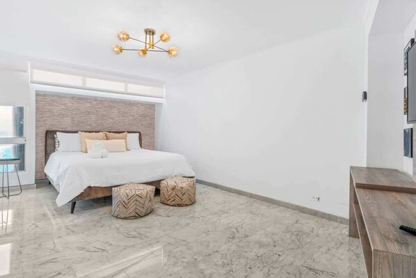 A modern bedroom with a large bed, a wooden headboard, and a hanging light fixture.