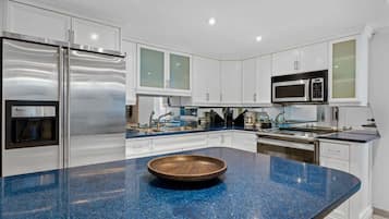 Une cuisine moderne avec des meubles blancs, des appareils en acier inoxydable et un plan de travail en granit bleu.