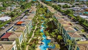 Een resort met een centraal gelegen zwembad, meerdere gebouwen en uitzicht op de oceaan.