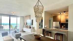 Una sala de estar moderna con comedor, cocina y balcón con vistas.