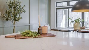 A modern kitchen with a marble countertop, a wooden cutting board, a bottle of reed diffuser, and a potted plant. - 105 Verbier Building 14 (Mont-Tremblant)