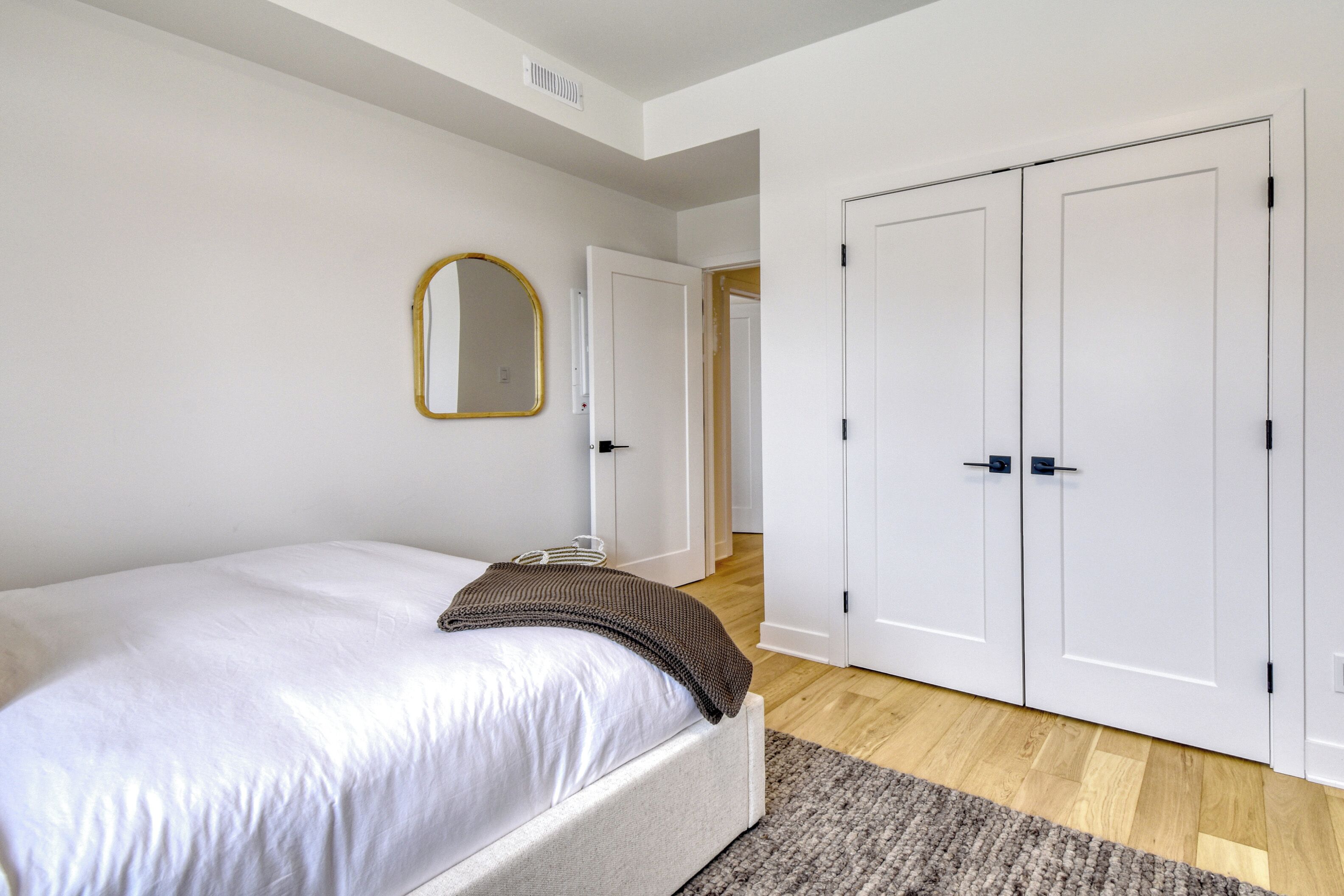 A bedroom with a bed, a mirror, and a wardrobe.