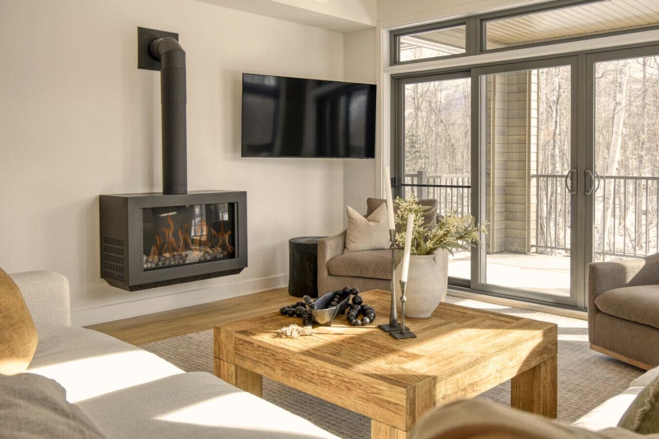 A modern living room with a fireplace, a flat-screen TV, and a large sliding glass door to the outdoors.