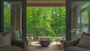 A balcony with a fire pit, seating, and a view of a forest. - 105 Verbier Building 14 (Mont-Tremblant)