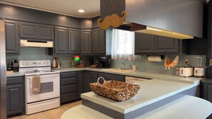 Una cocina moderna con armarios gris oscuro, una estufa blanca y una isla grande con una cesta trenzada.