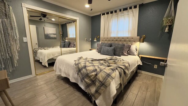 Un dormitorio con una cama grande, un espejo y un ventilador de techo.