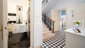 A staircase with a black and white checkered floor, leading to a room with white walls and a white door.