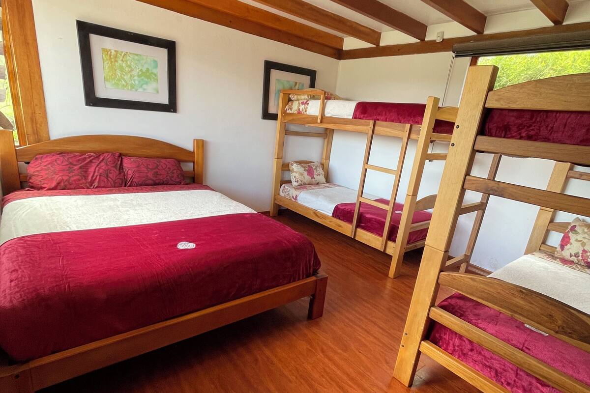 Una habitación con una litera de madera, una cama individual y un techo de madera con vigas a la vista.