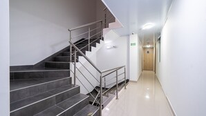 A modern hotel interior with a staircase, a hallway, and a wooden door at the end. - DOXA HOTEL (Medellín)