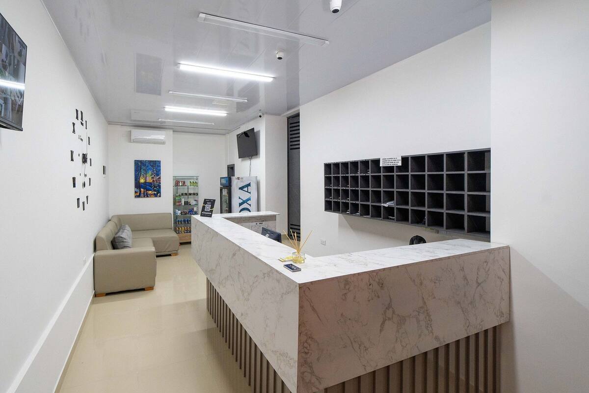 A modern reception area with a marble counter, a sofa, and a television mounted on the wall.