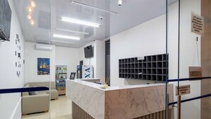 A reception area with a marble counter, a sofa, and a wall-mounted TV. - DOXA HOTEL (Medellín)
