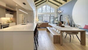 Una cocina amplia con una isla grande, vigas de madera en el techo y vistas al exterior a través de ventanas amplias.