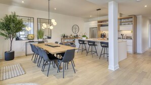 Una cocina moderna con una isla central, taburetes de bar y un comedor con una mesa y sillas de madera.