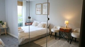 Ein modernes Schlafzimmer mit einem großen Bett, Nachttischen, einem Sessel und einem Spiegel.