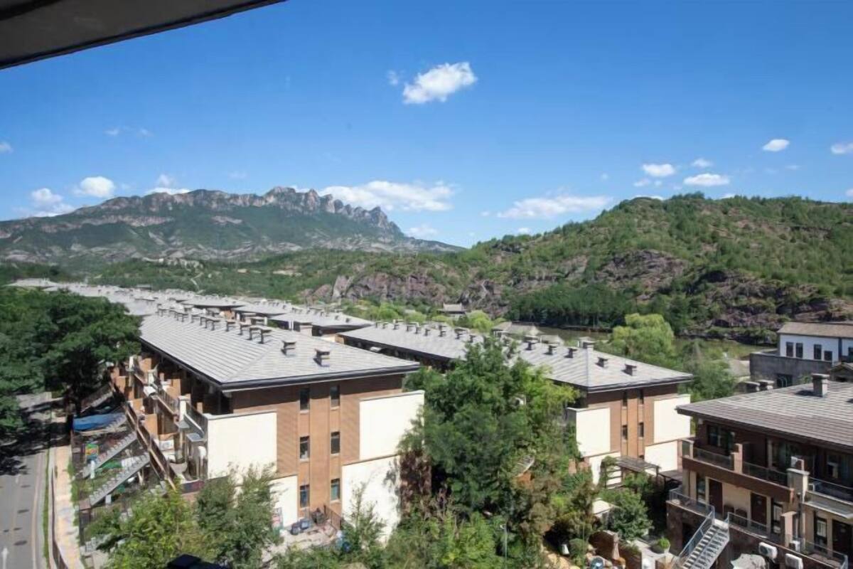Un quartier résidentiel avec des bâtiments modernes, une vue dégagée sur une montagne et une route au premier plan.