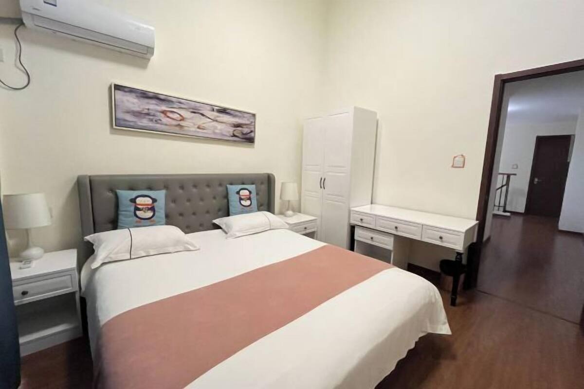 Une chambre d’hôtel avec un lit, un bureau, une armoire et un tableau au mur.