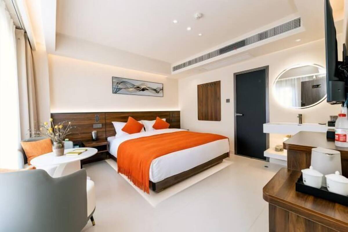 A modern hotel room with a bed, bedside table, and a mirror.