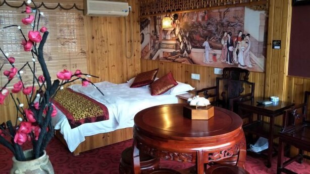 A traditional room with a bed, a wooden table, and a painting on the wall. - Hongcun Lexian · Villa Hui-style Light Luxury Vacation Homestay (Nanhu) (Yi County)