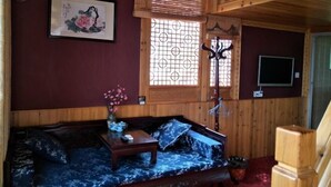 A wooden interior with a sofa, a small table, a TV, and a window with a decorative screen. - Hongcun Lexian · Villa Hui-style Light Luxury Vacation Homestay (Nanhu) (Yi County)
