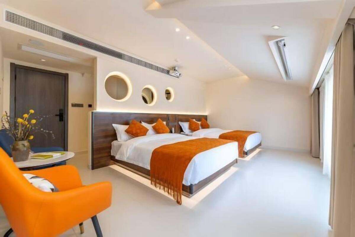 A modern hotel room with a large bed, a desk, and a chair.