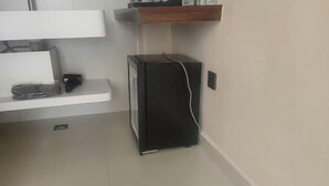 A small black refrigerator with a power cord, a white countertop, and a wooden shelf above. - Hongcun Lexian · Villa Hui-style Light Luxury Vacation Homestay (Nanhu) (Yi County)