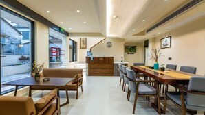 A modern hotel lobby with a reception desk, a long dining table with chairs, and a staircase leading to an upper floor. - Hongcun Lexian · Villa Hui-style Light Luxury Vacation Homestay (Nanhu) (Yi County)