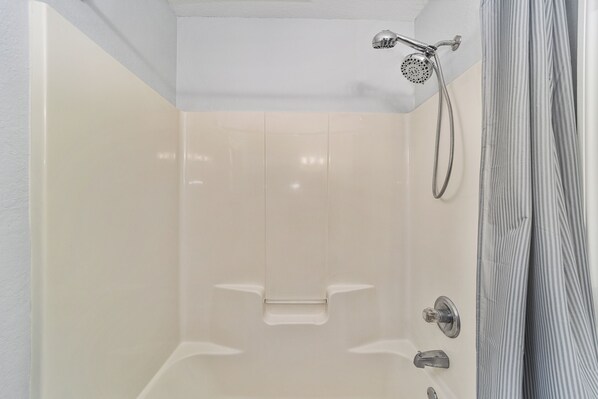 Un bagno moderno con una vasca, un soffione doccia e un porta asciugamani.