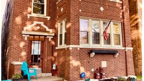 A brick building with a front entrance, windows, and an American flag.