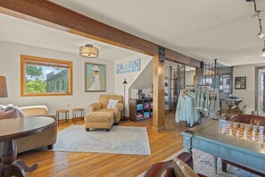 A spacious living room with a large chess table, a cozy seating area, and a view of the outdoors through a large window. - Roadrunner Inn and Log Cabins (Eureka Springs)