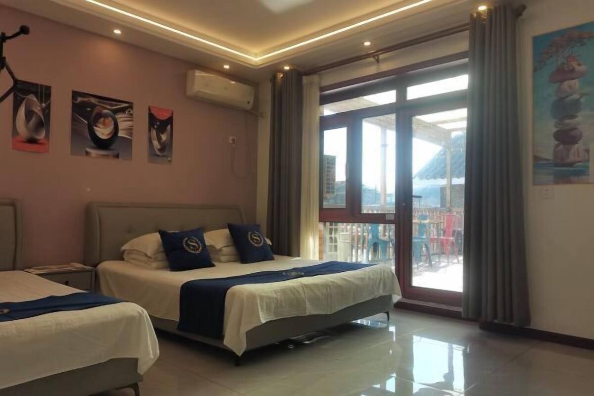 A hotel room with two beds, a large sliding glass door to the balcony, and artwork on the walls.