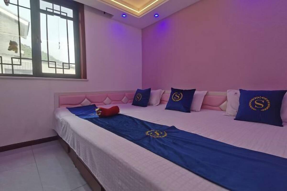 A bedroom with a bed, pillows, a blanket, and a window.