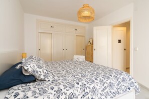 A bedroom with a bed, a wardrobe, and a hanging light fixture.