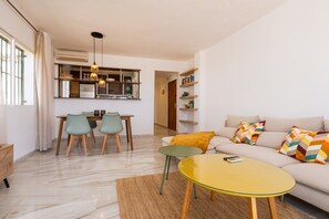 Una sala de estar moderna con un sofá, una mesa de centro y un comedor con sillas y una mesa.