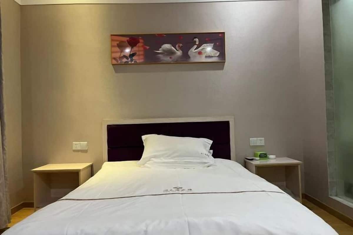 A hotel room with a bed, two bedside tables, a nightstand, a painting, and a window.