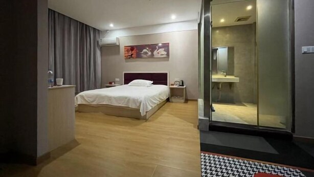 A modern hotel room with a bed, bedside table, and a glass-enclosed shower area. - Zhongxiangshun Tianyuan Business Hotel (Zhongxiang)