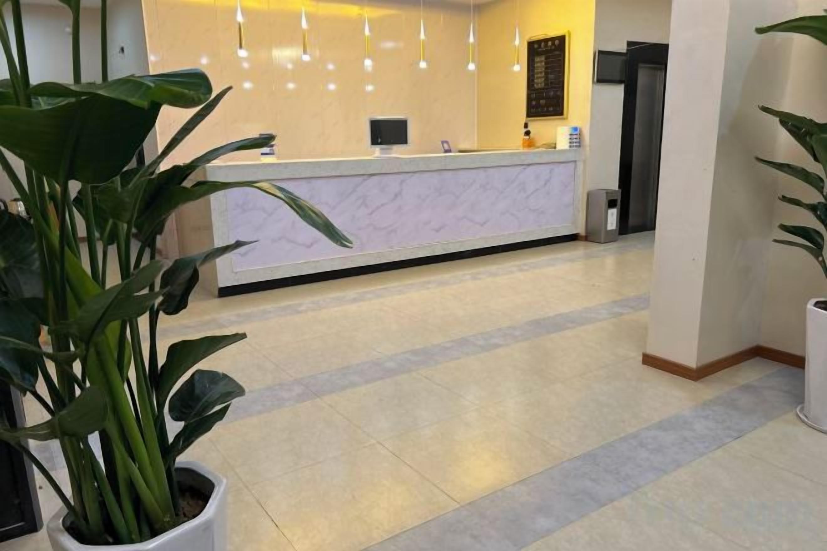 A reception area with a marble counter, potted plants, and a tiled floor.
