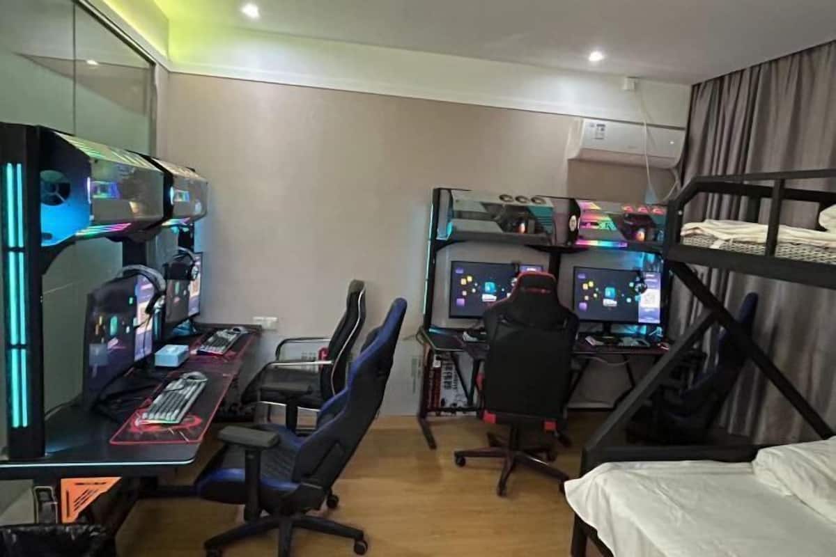 A room with a bunk bed, a desk with a computer setup, and a chair.